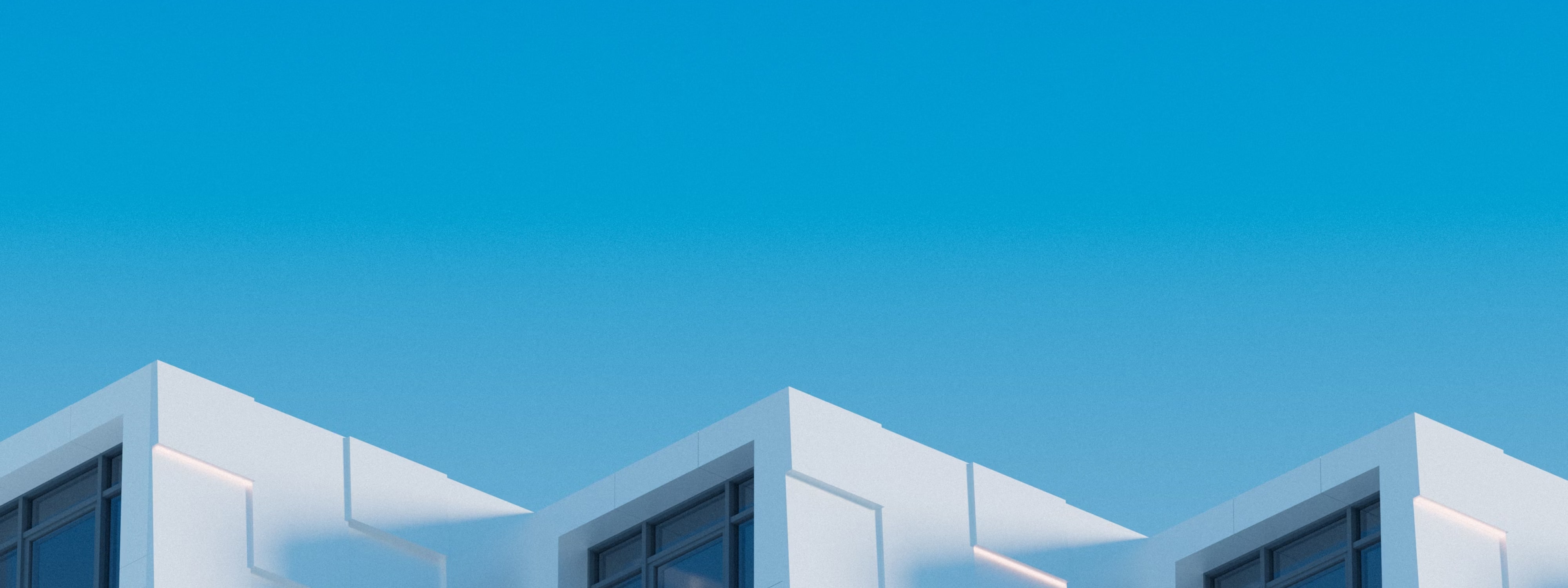 Modern white buildings with large windows against a clear blue sky