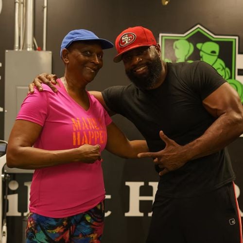 Two people posing together at gym, wearing colorful workout clothes and caps