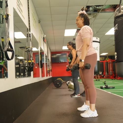 Two women exercising with weights in a gym fitness training area