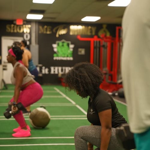 Two people exercising with weights and kettlebells in fitness gym