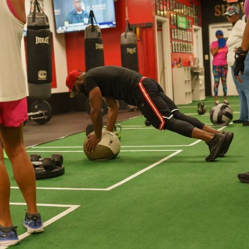 Athlete doing medicine ball exercise on green floor in fitness gym